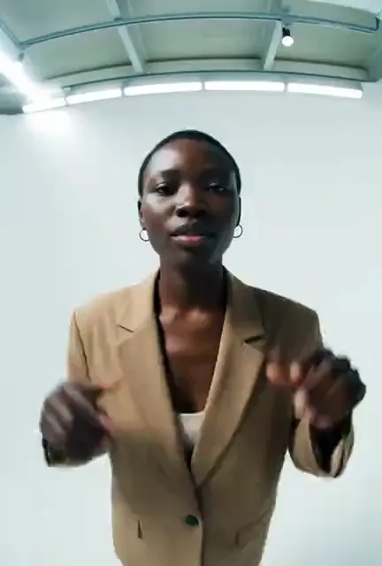 Video preview: Studio fashion gestures — An adult fashion model in a brown outfit poses expressively in a photography studio, warm light and natural hand movements.
